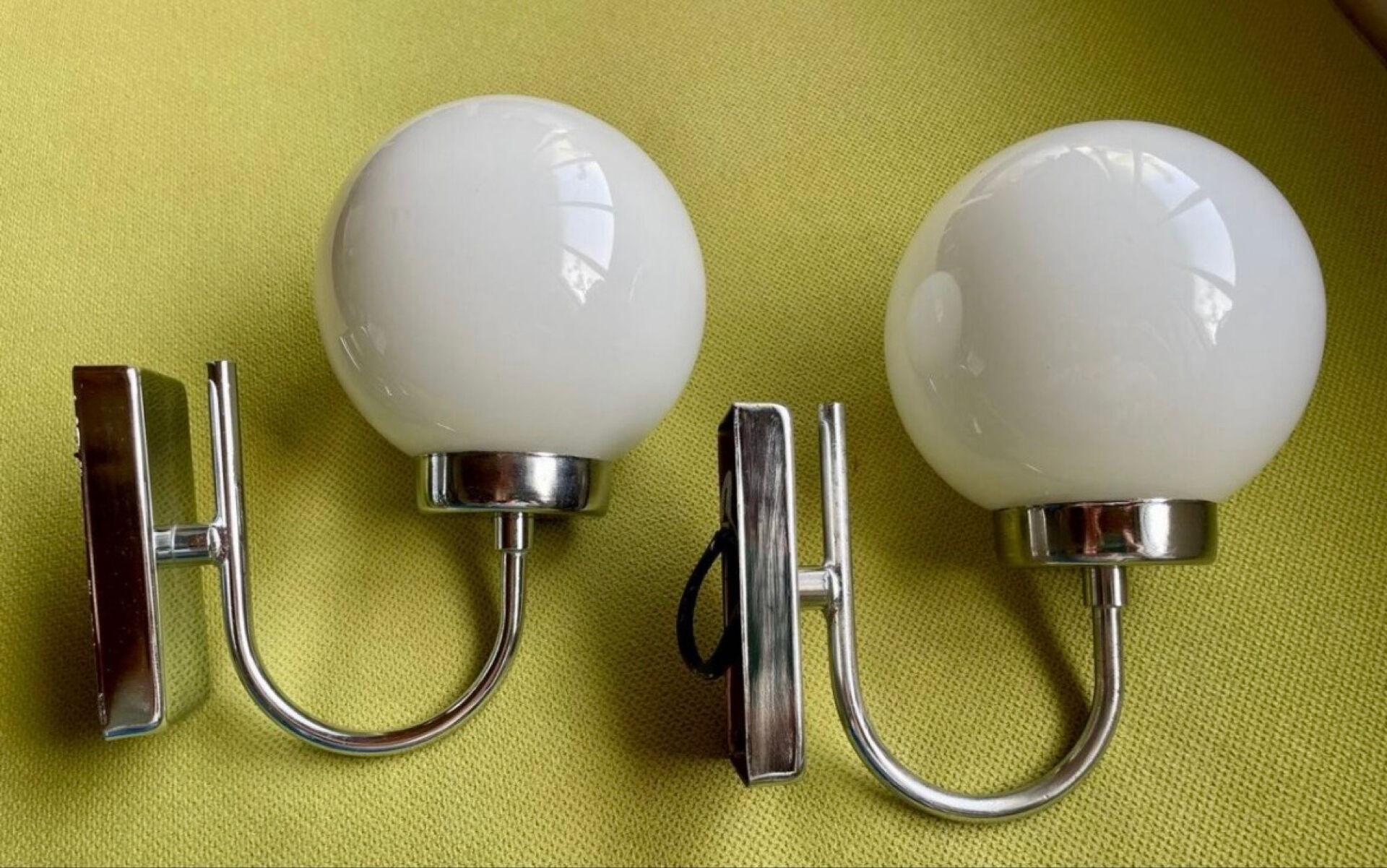 Pair of chrome metal wall lights with white glass globe.