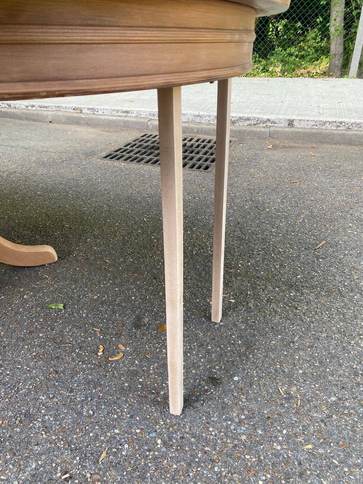 Large extendable round dining table stripped in solid cherry wood with a central leg.