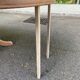 Large extendable round dining table stripped in solid cherry wood with a central leg.