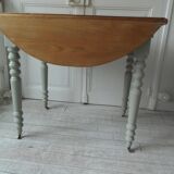 Walnut table with raised flaps, base on verdigris casters.