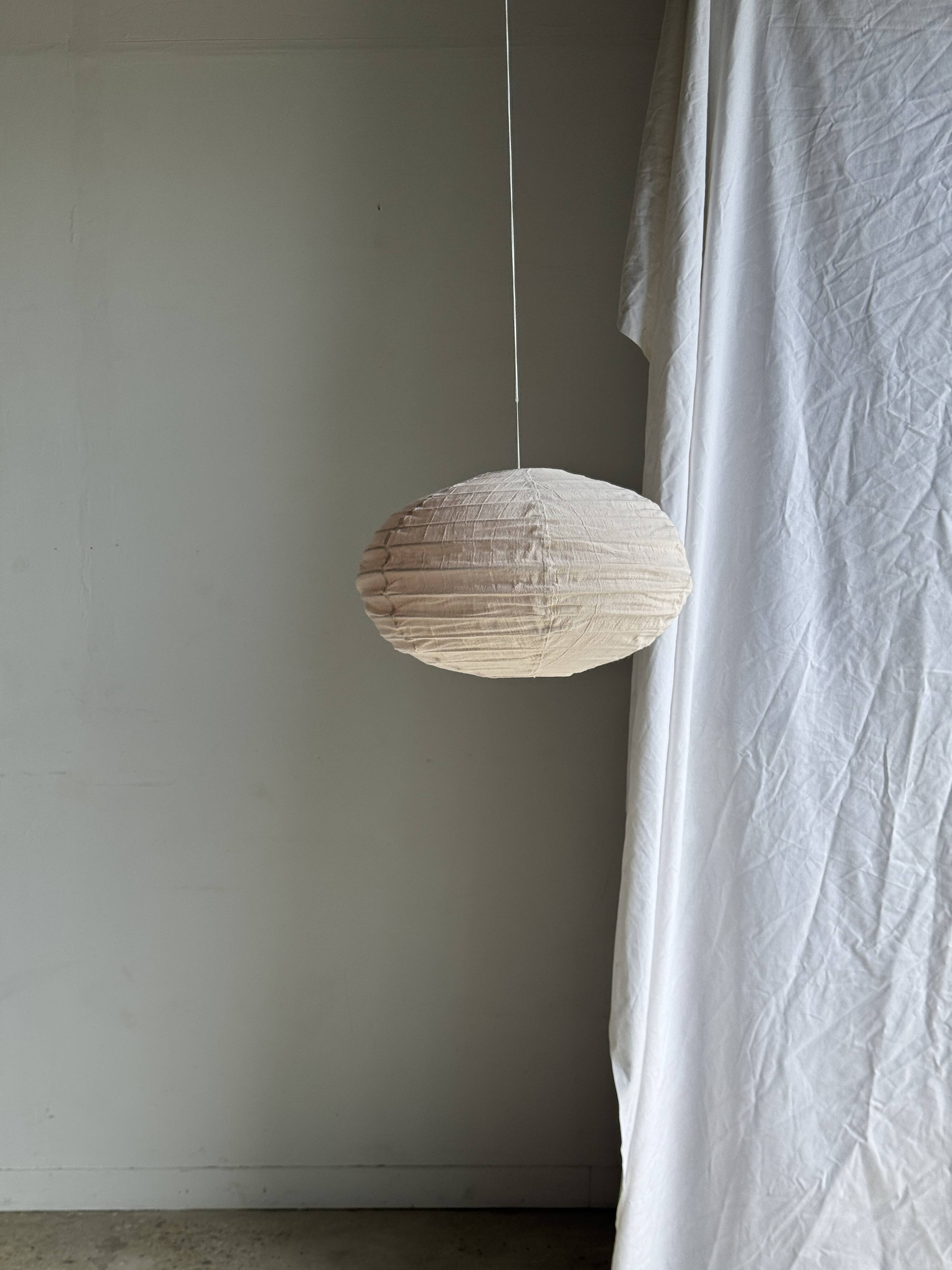 Average suspension in natural rattan and linen, Japanese-style, flattened oval in pink.