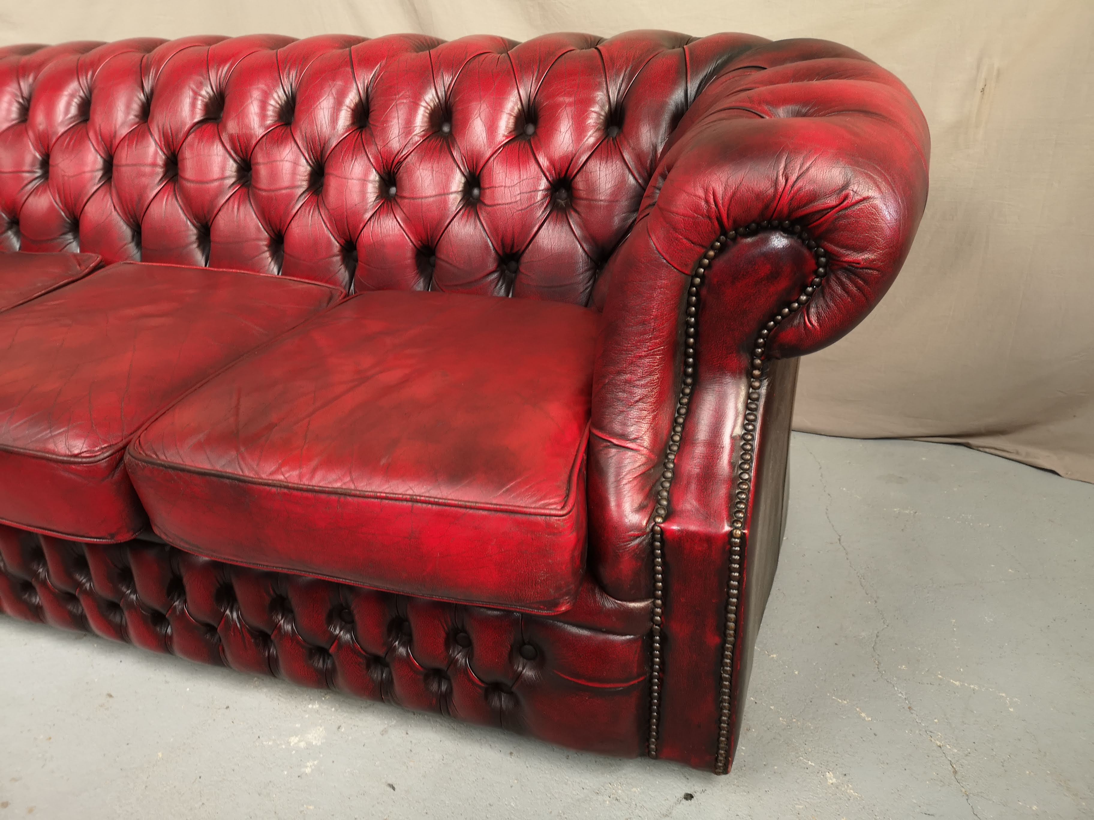 Three-seater curved red leather chesterfield sofa