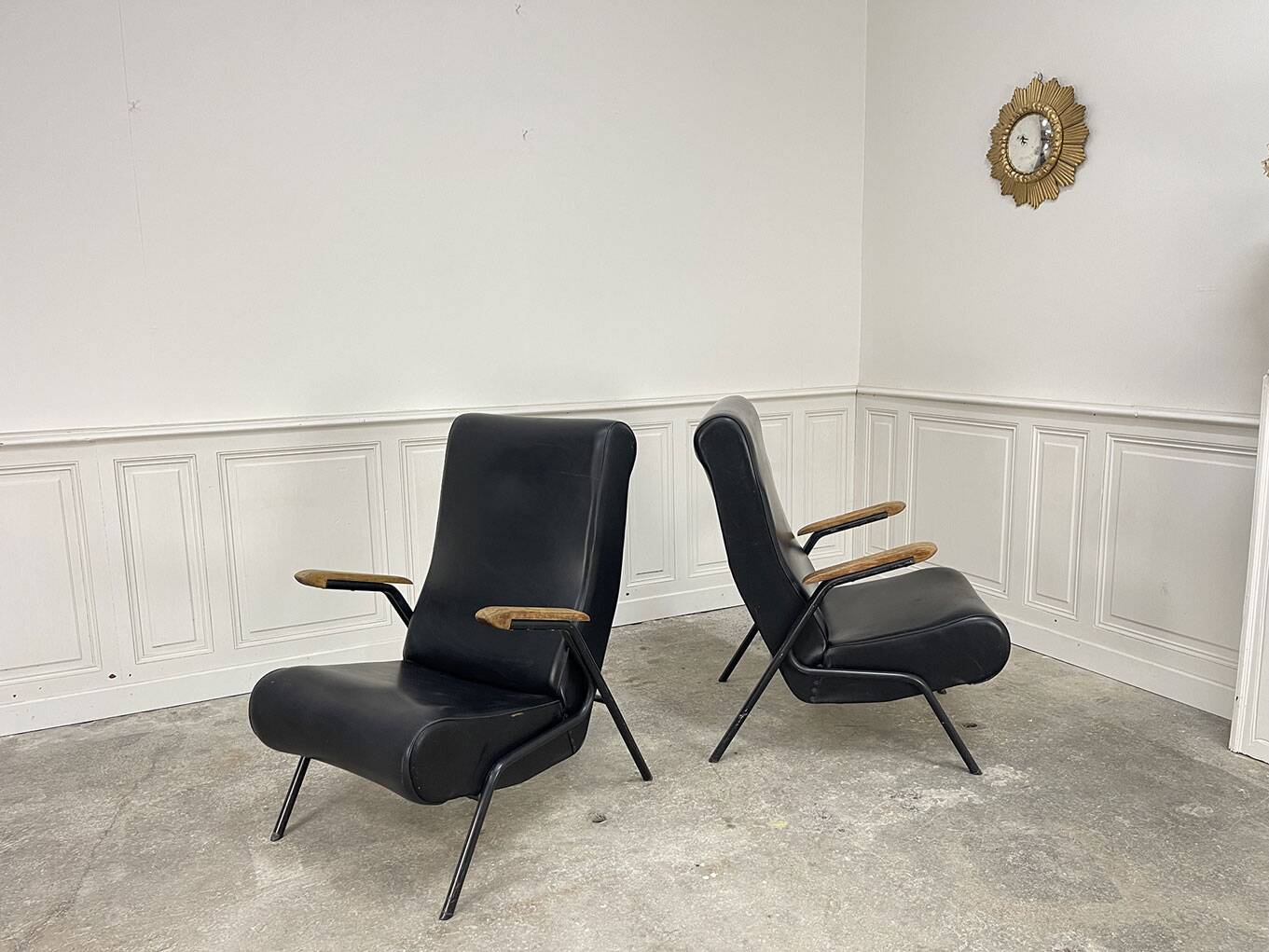 A pair of vintage armchairs in black faux leather.
