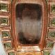 Wall-mounted candleholder in earthy, greenish, golden colours and shades.