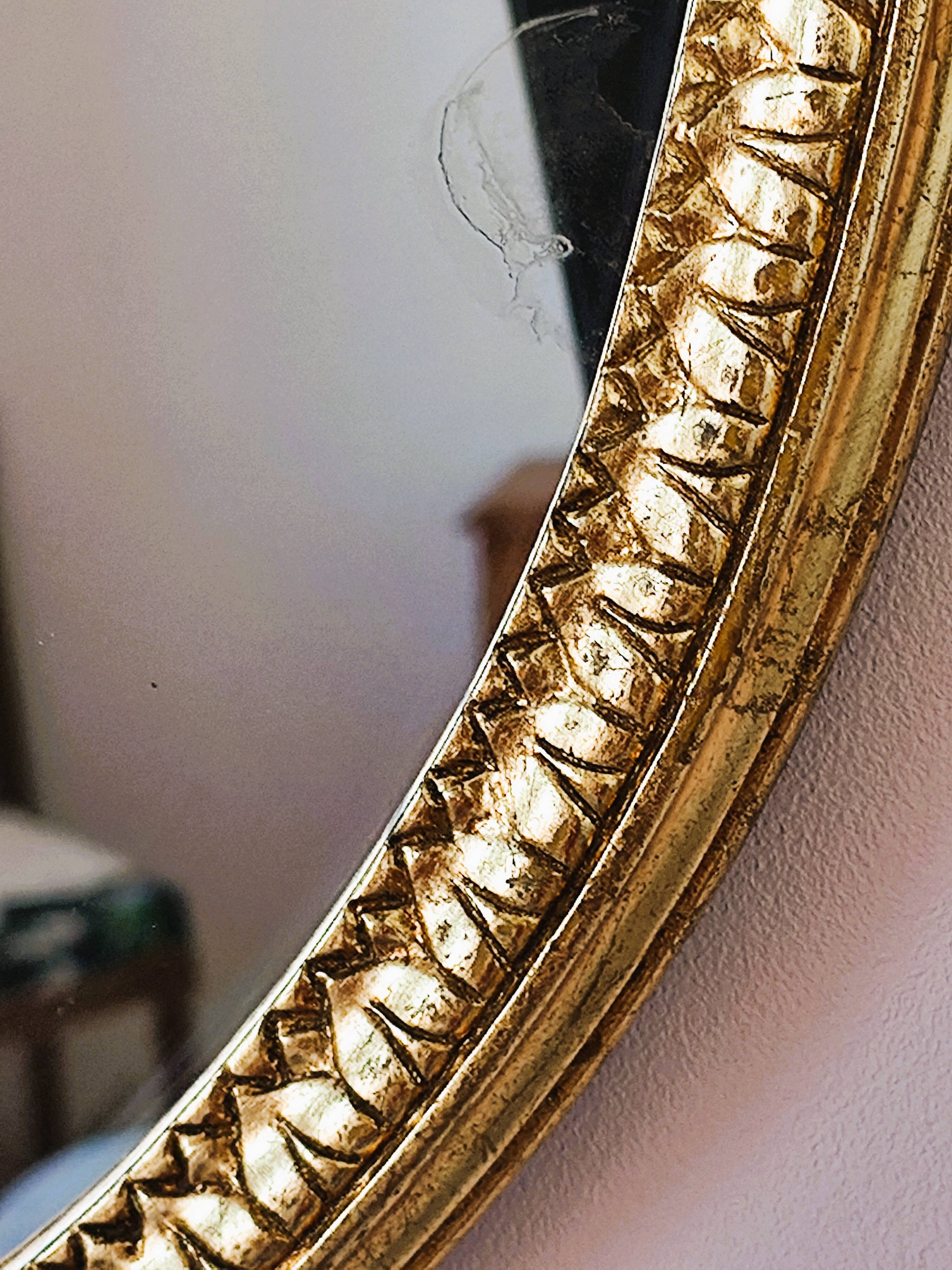 Oval mirror in gilded wood with a pediment.