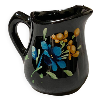 Small black earthenware creamer with blue and yellow flower decoration