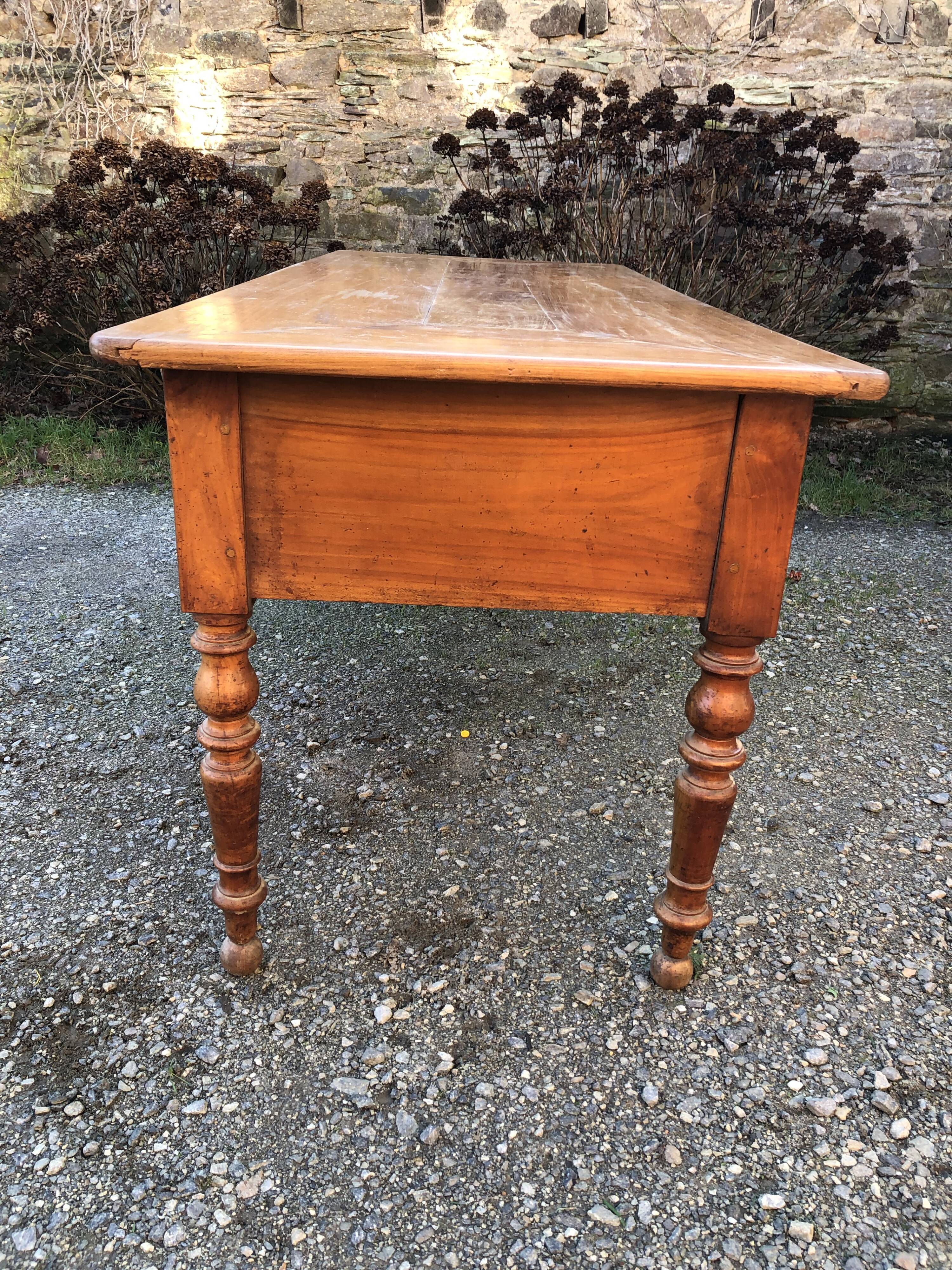 Antique cherry farmhouse table with turned legs and 2 drawers.