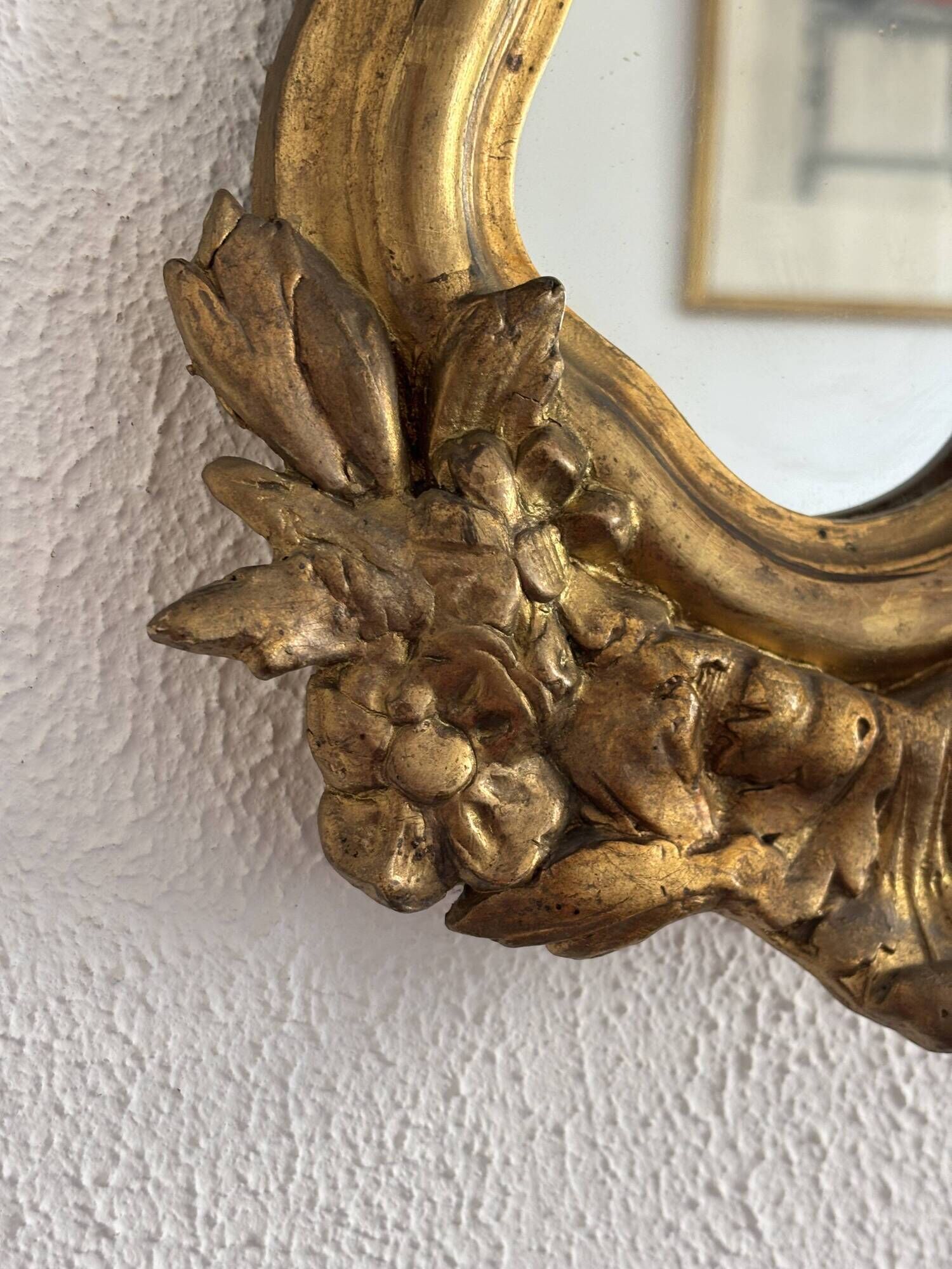 Antique rococo mirror with putti, gilded carved wood and stucco frame, 19th century.