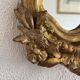 Antique rococo mirror with putti, gilded carved wood and stucco frame, 19th century.