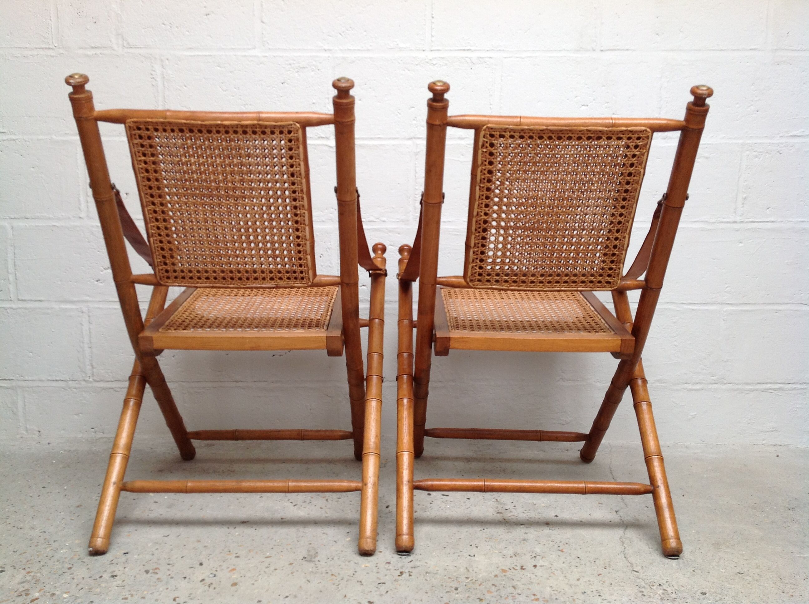 Pair of folding chairs in bamboo and caning, leather and brass