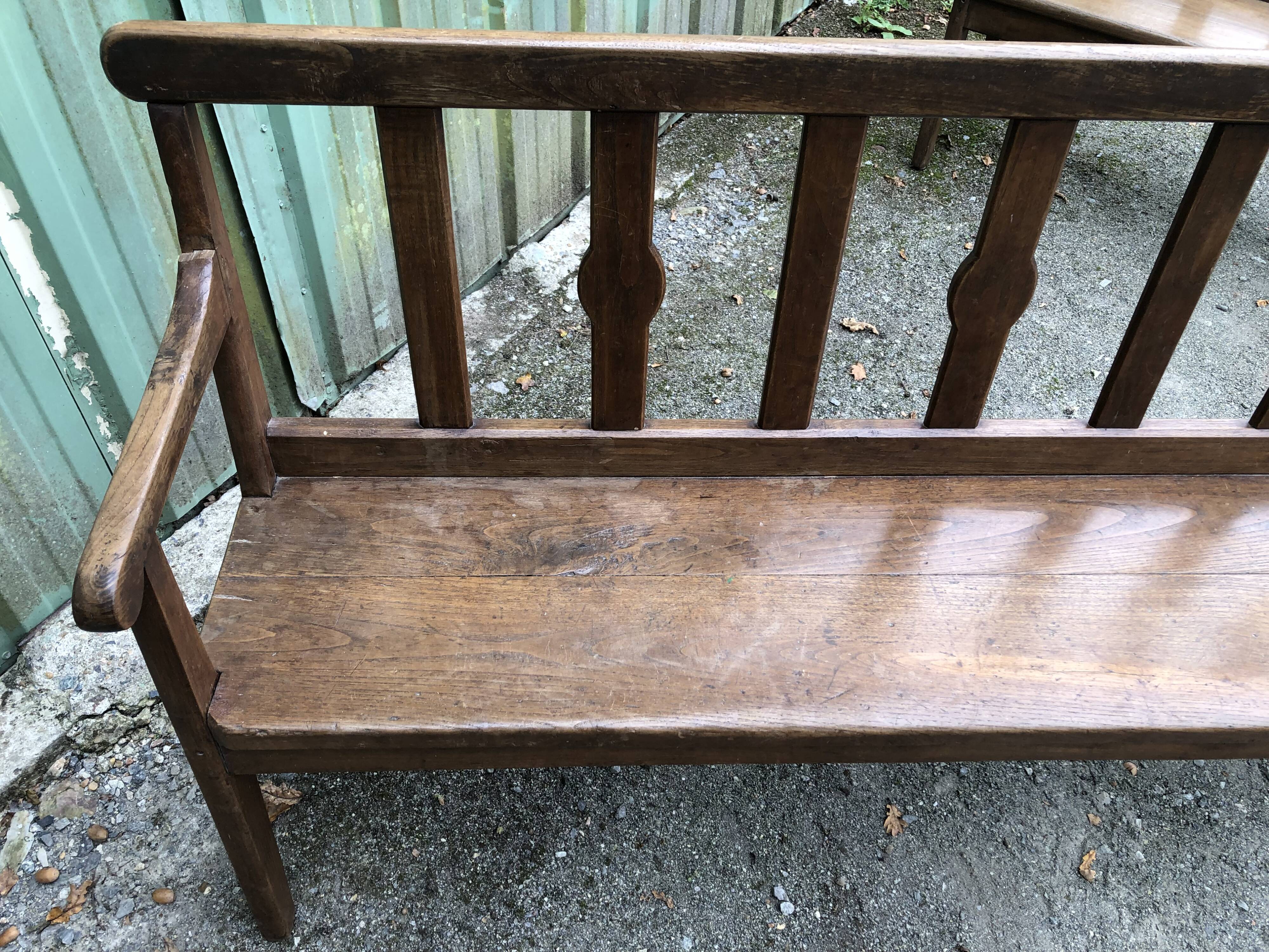 Duo of old solid oak benches with backs and armrests.