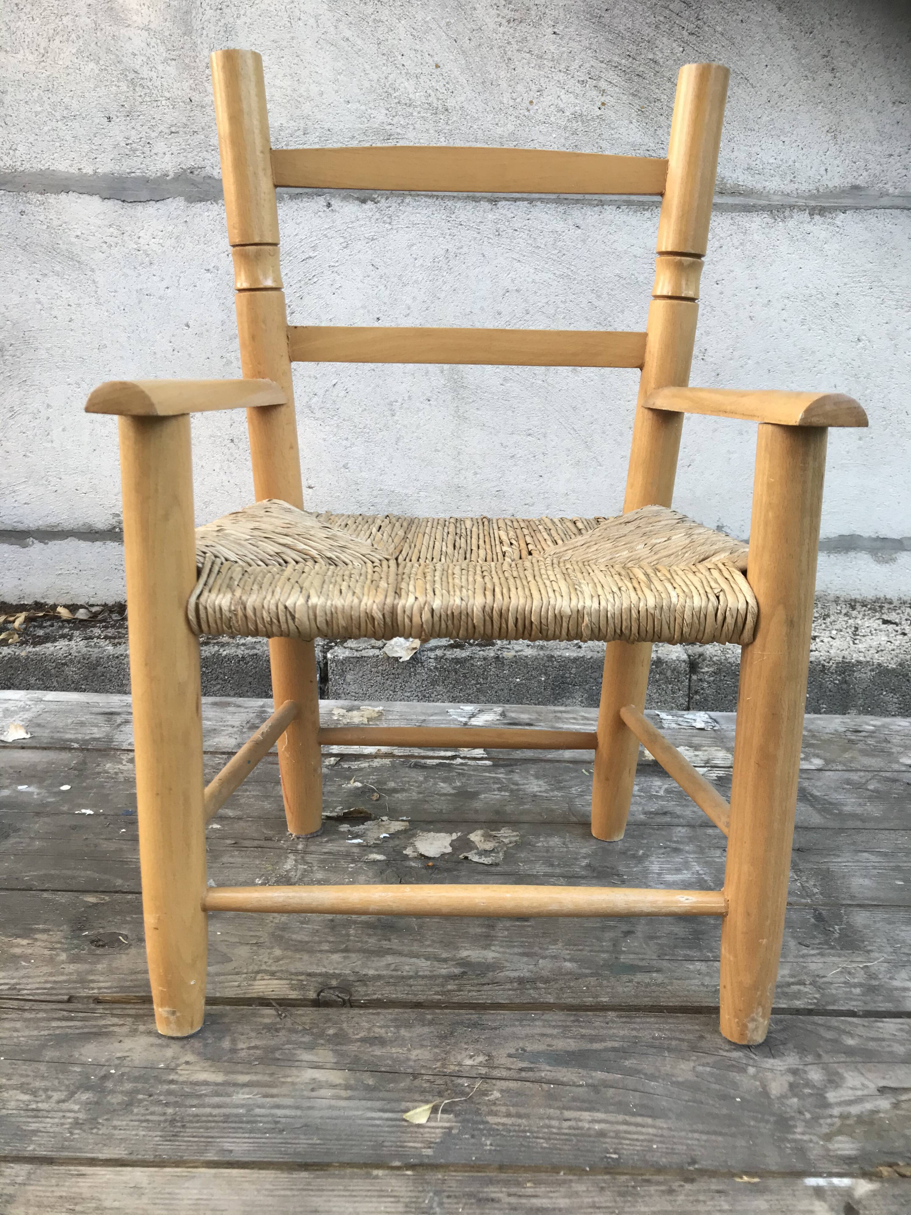 Old wooden children's armchair and vintage woven straw seat