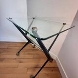 Table with thick glass top and black steel legs with casters