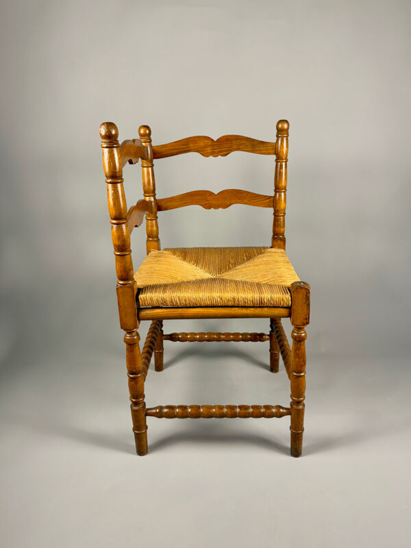 Chaise d'angle vintage en bois avec assise en paille tissée.