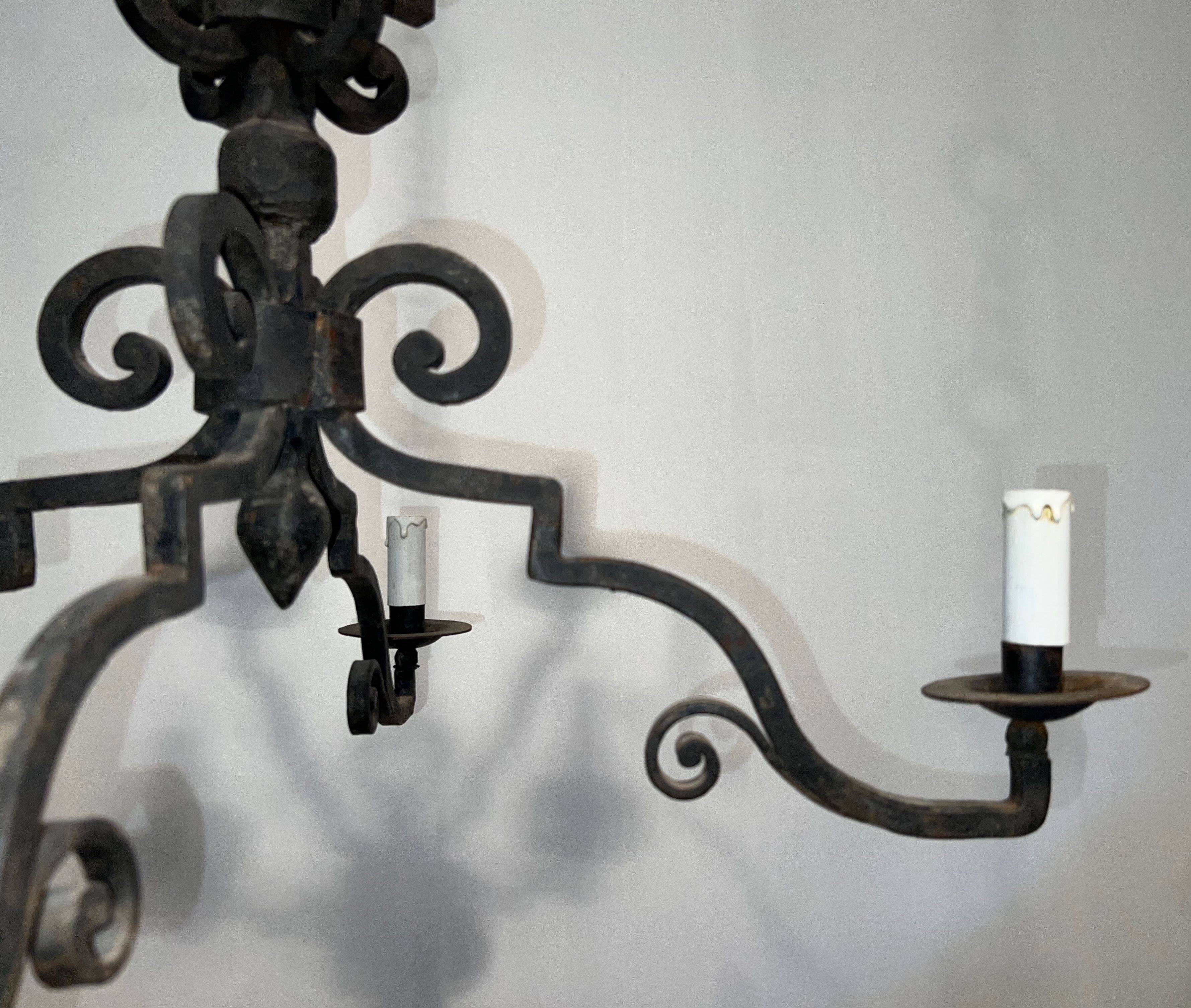 Two-tiered wrought iron chandelier with eight light arms in Gothic style.