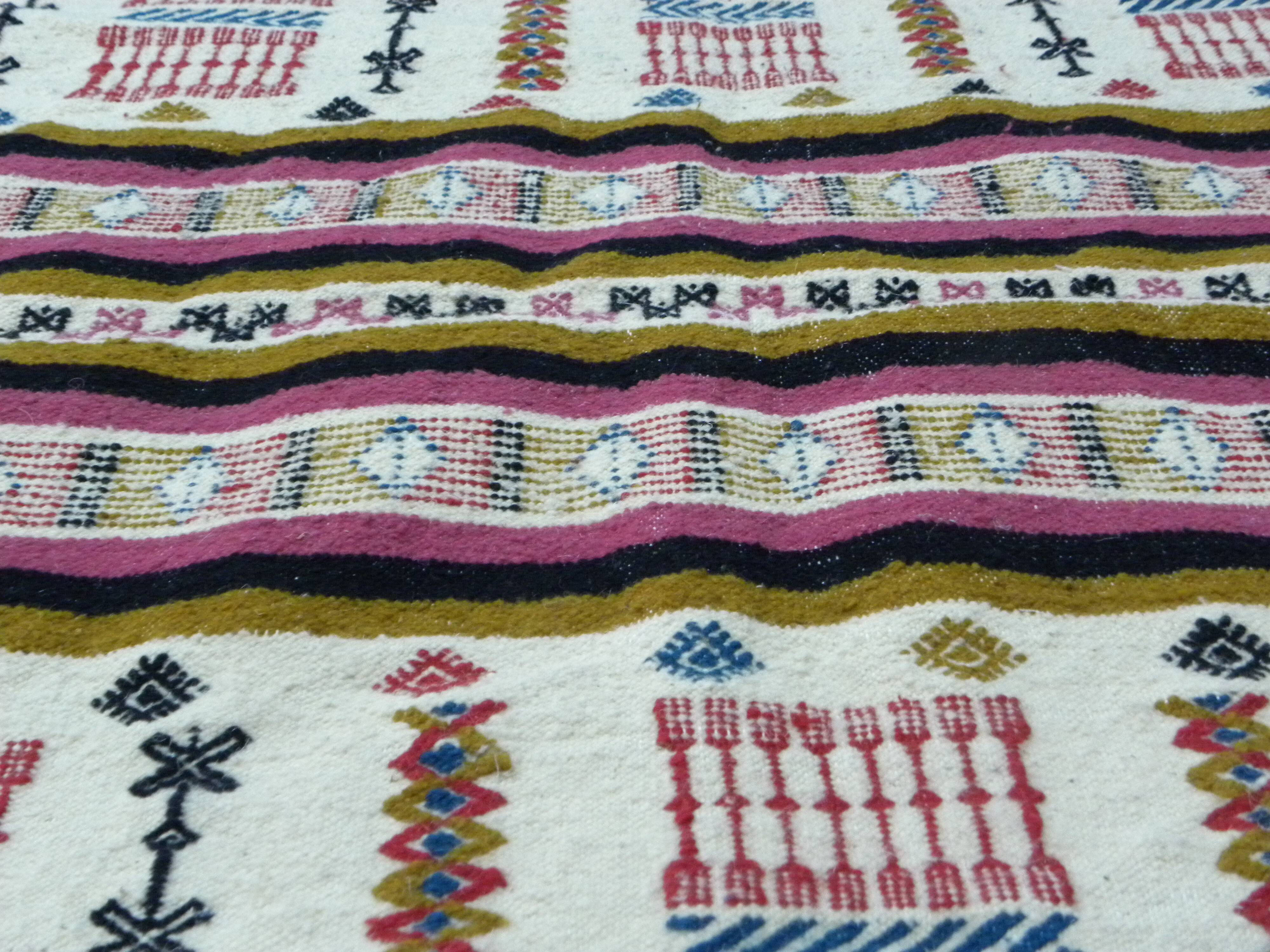 Handmade Berber kilim rug with multicoloured tribal motifs.