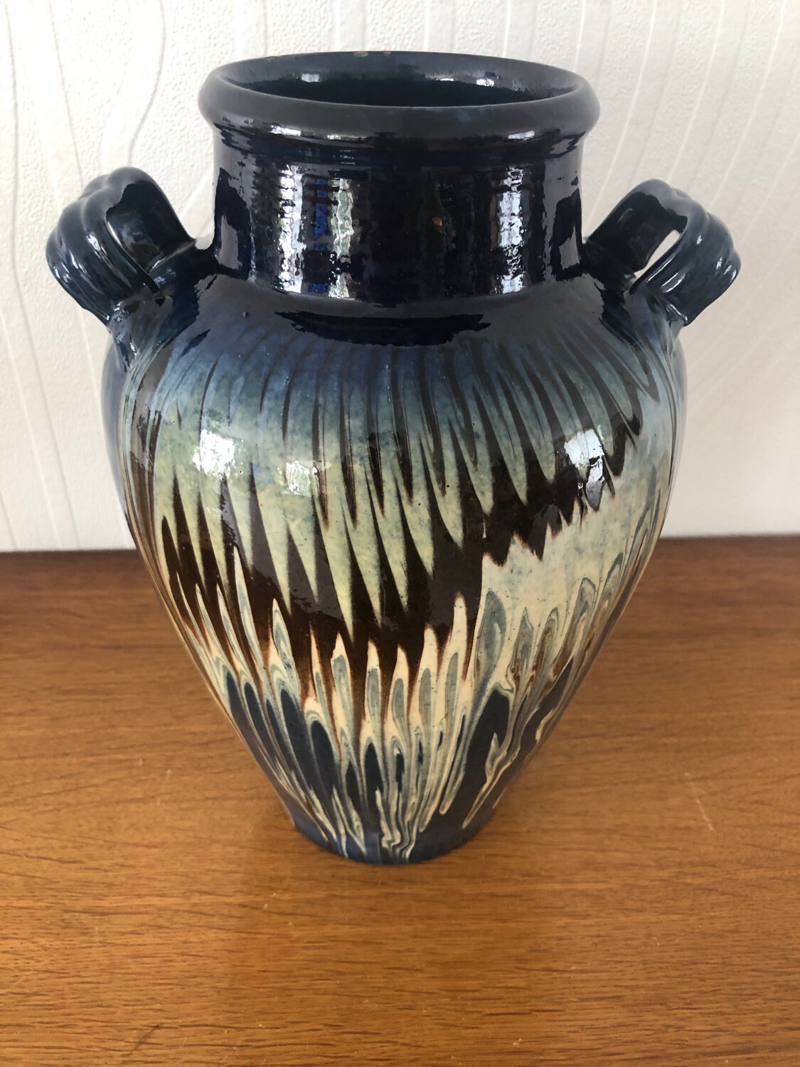 Vase in glazed ceramic decoration drips on blue background
