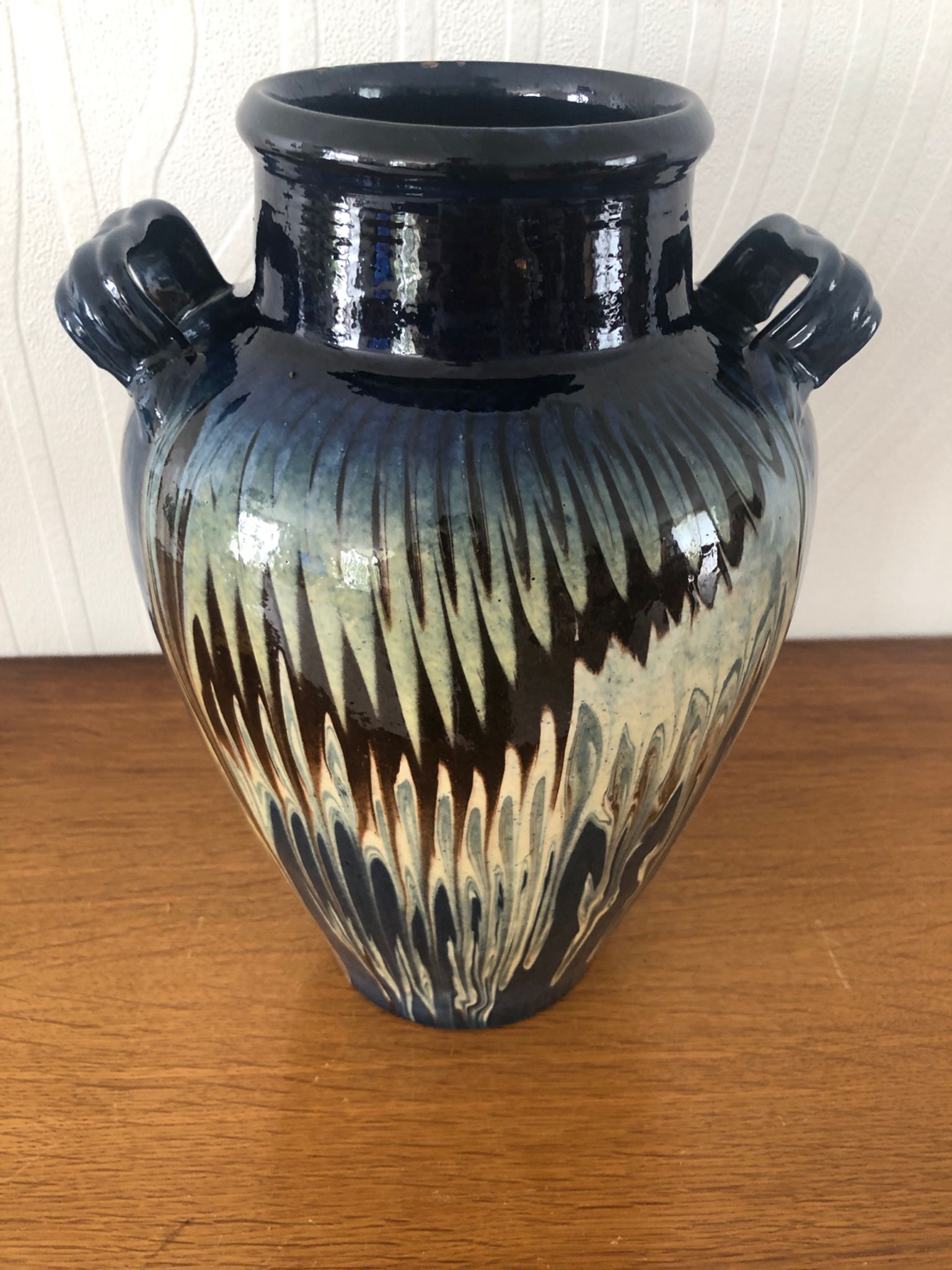 Vase in glazed ceramic decoration drips on blue background
