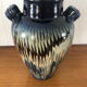 Vase in glazed ceramic decoration drips on blue background