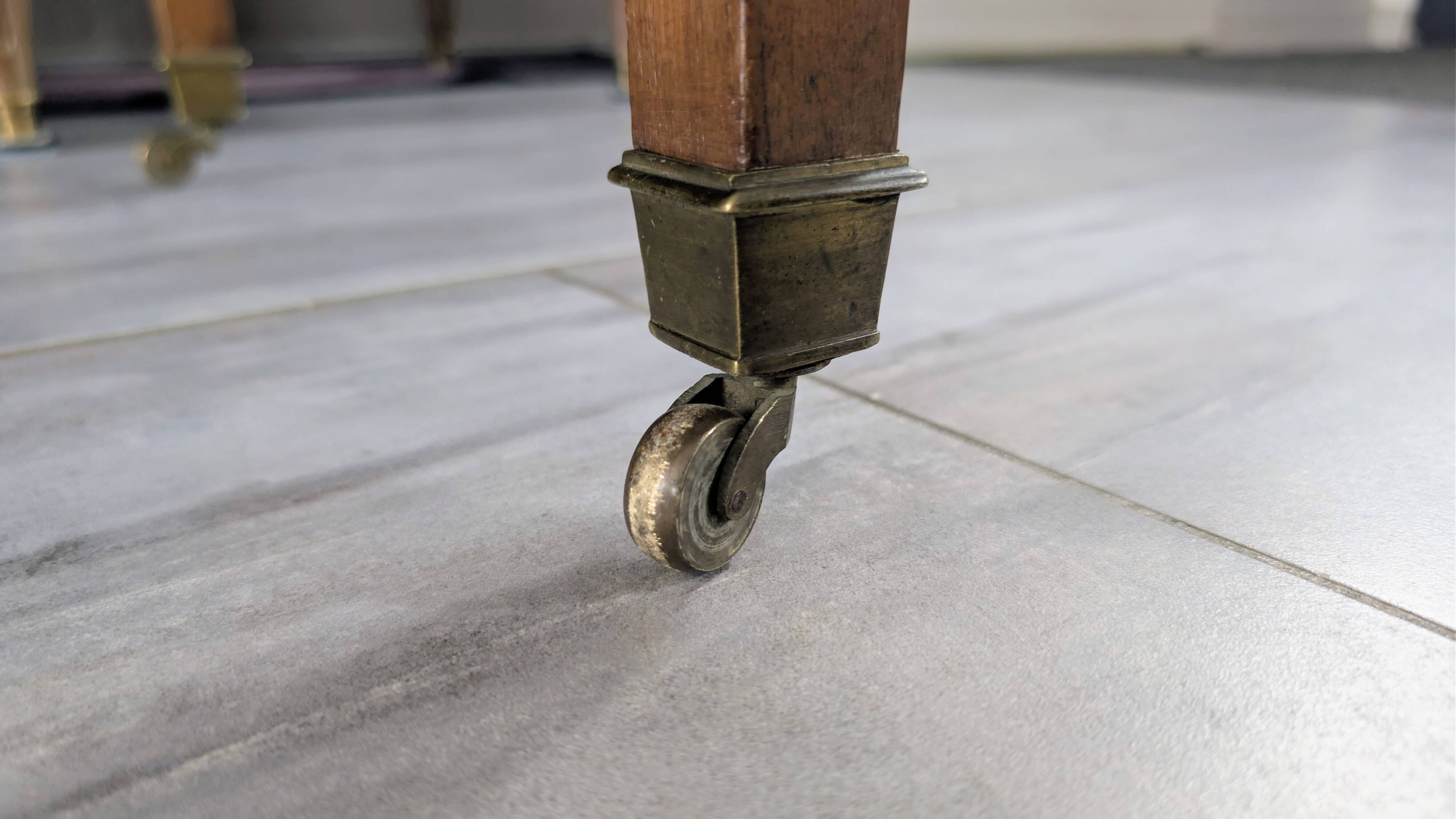 Antique wooden folding table with a patina and brass wheels.