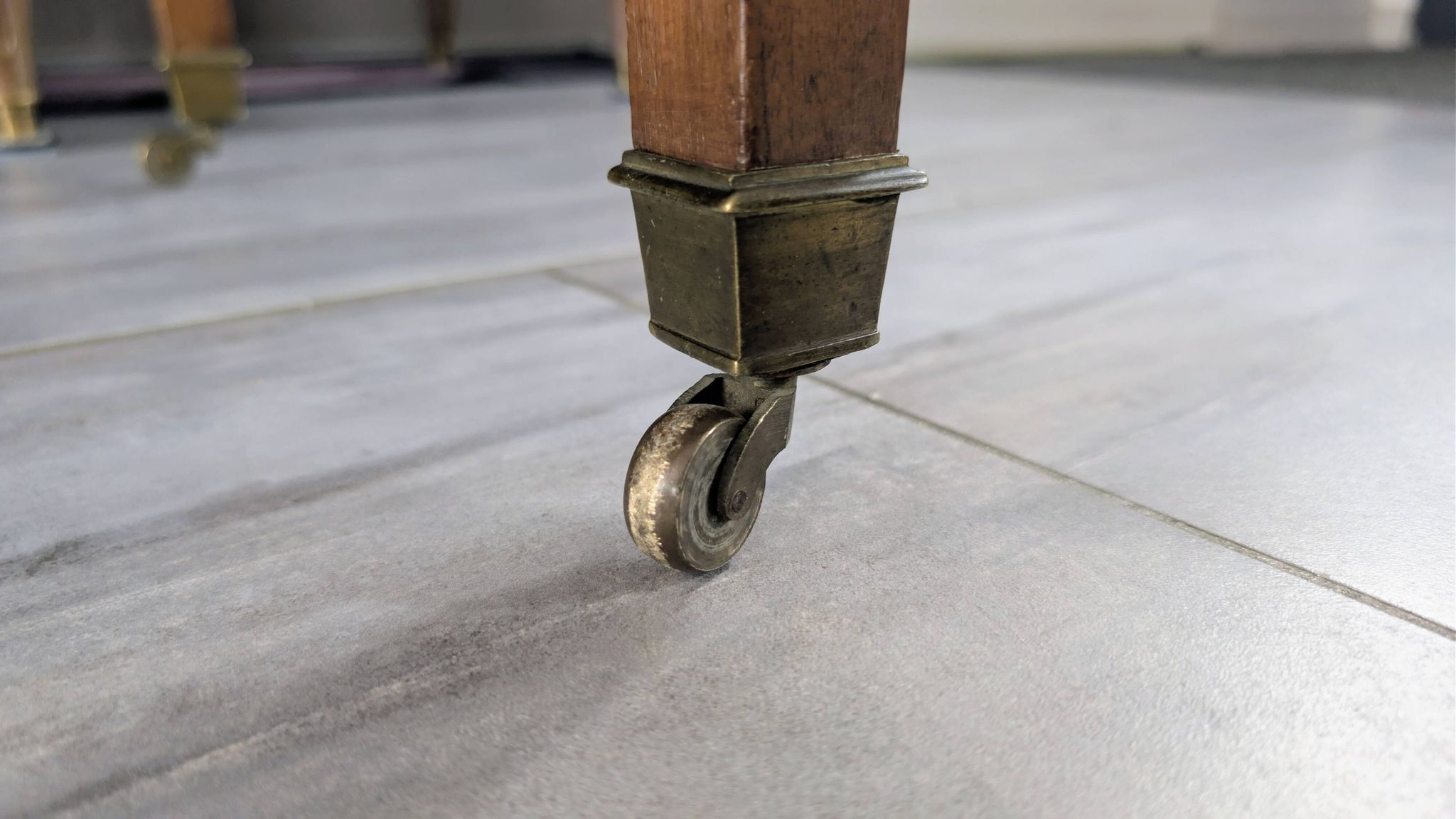 Antique wooden folding table with a patina and brass wheels.