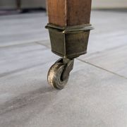Antique wooden folding table with a patina and brass wheels.