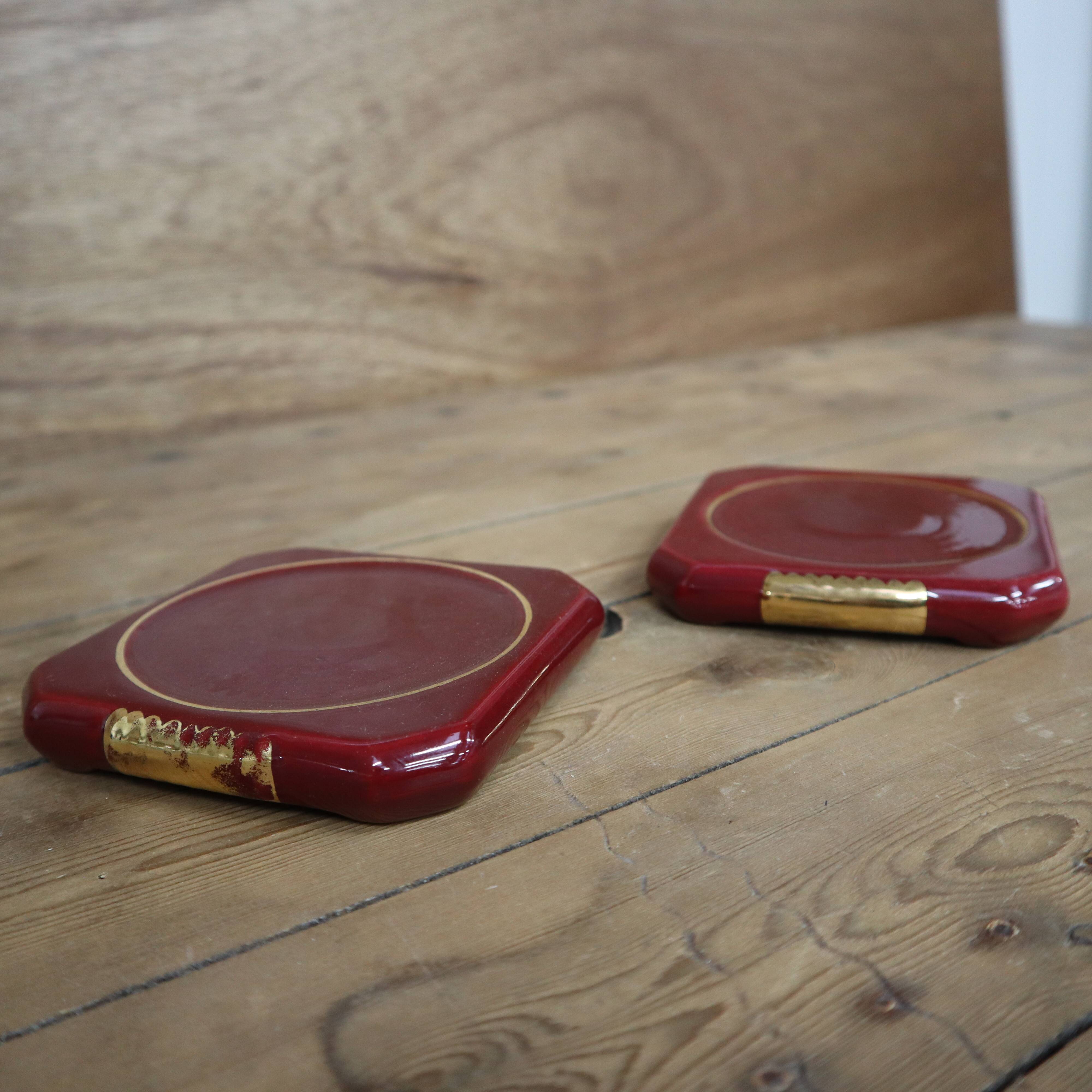 Pair of burgundy ceramic coasters or bottles with gold trim