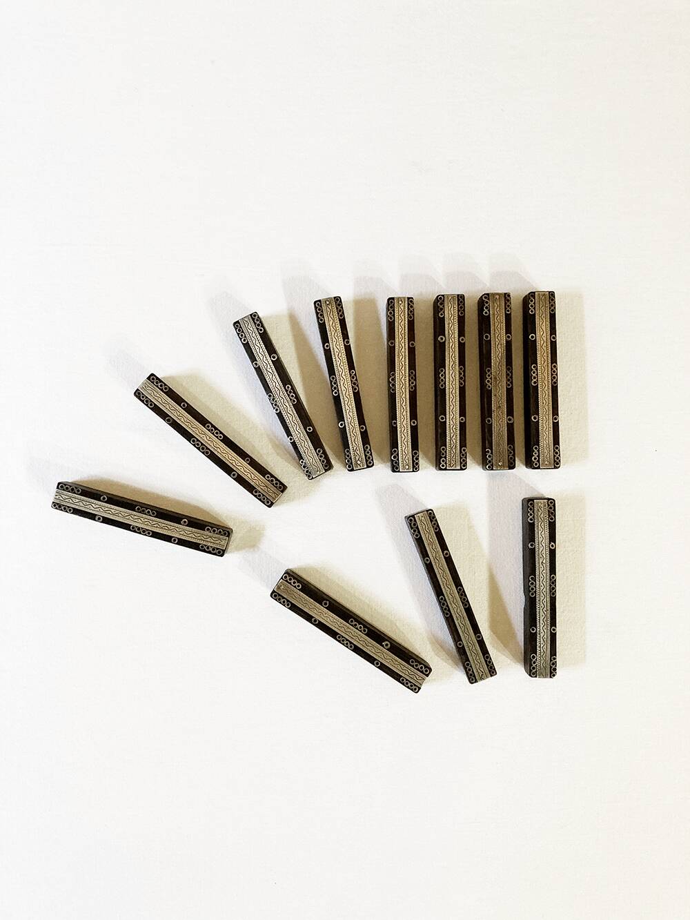 Set of 11 ebony wood knife rests with brass inlay