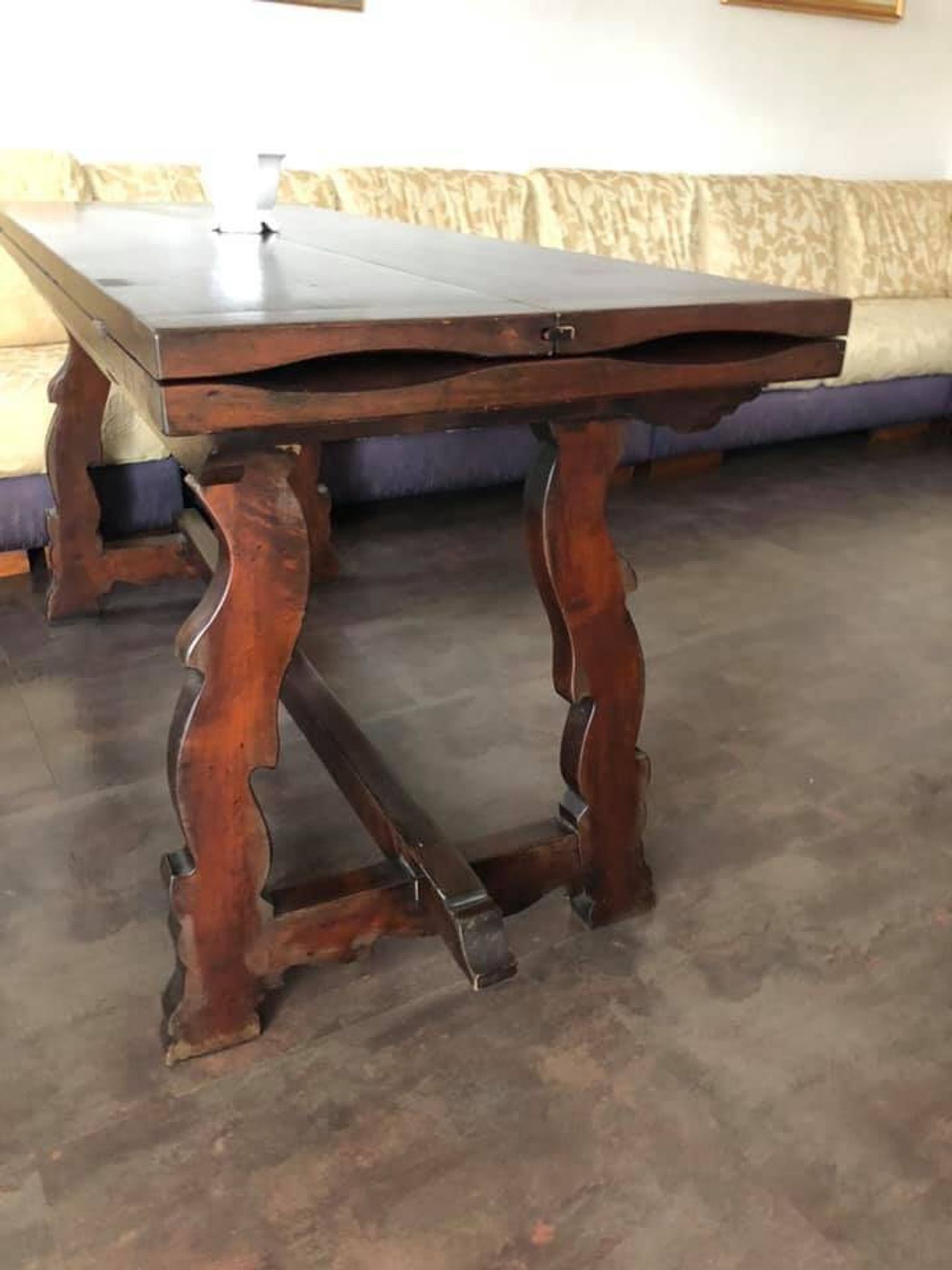 19th-century brown walnut dining table with sculpted trestle legs.