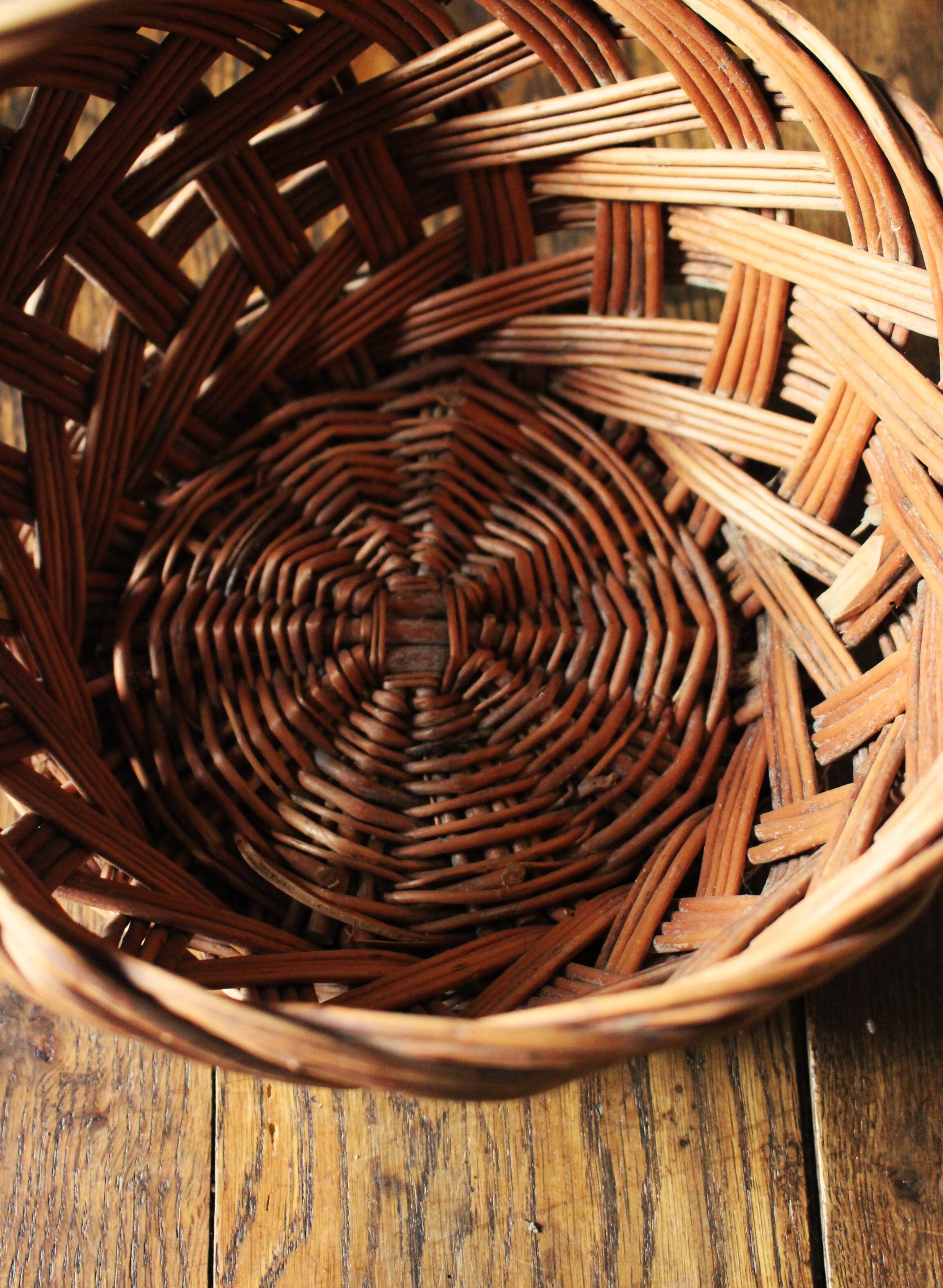Round woven dark wicker basket with openwork vintage handle