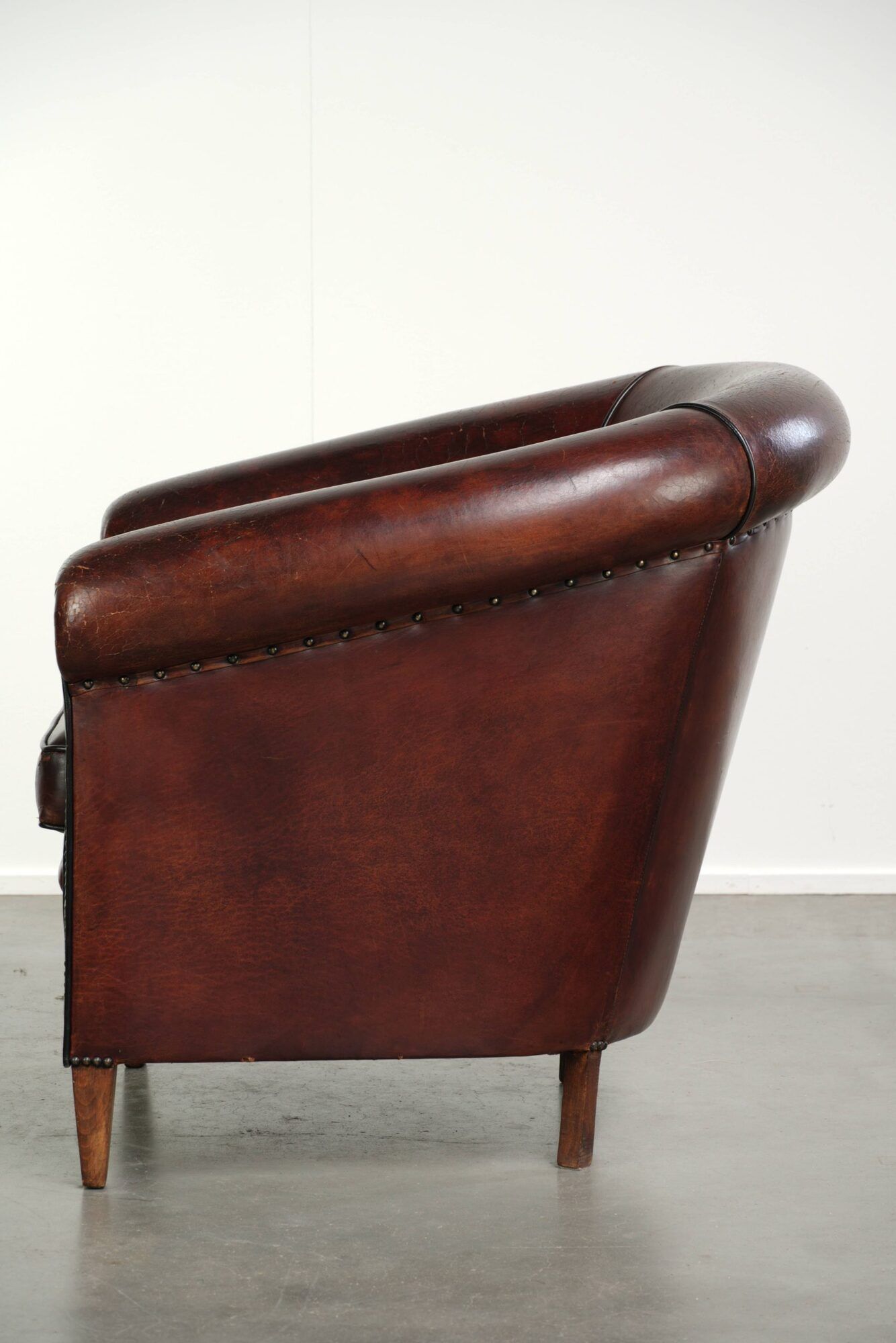 Vintage sheepskin club armchair with decorative nails and black piping