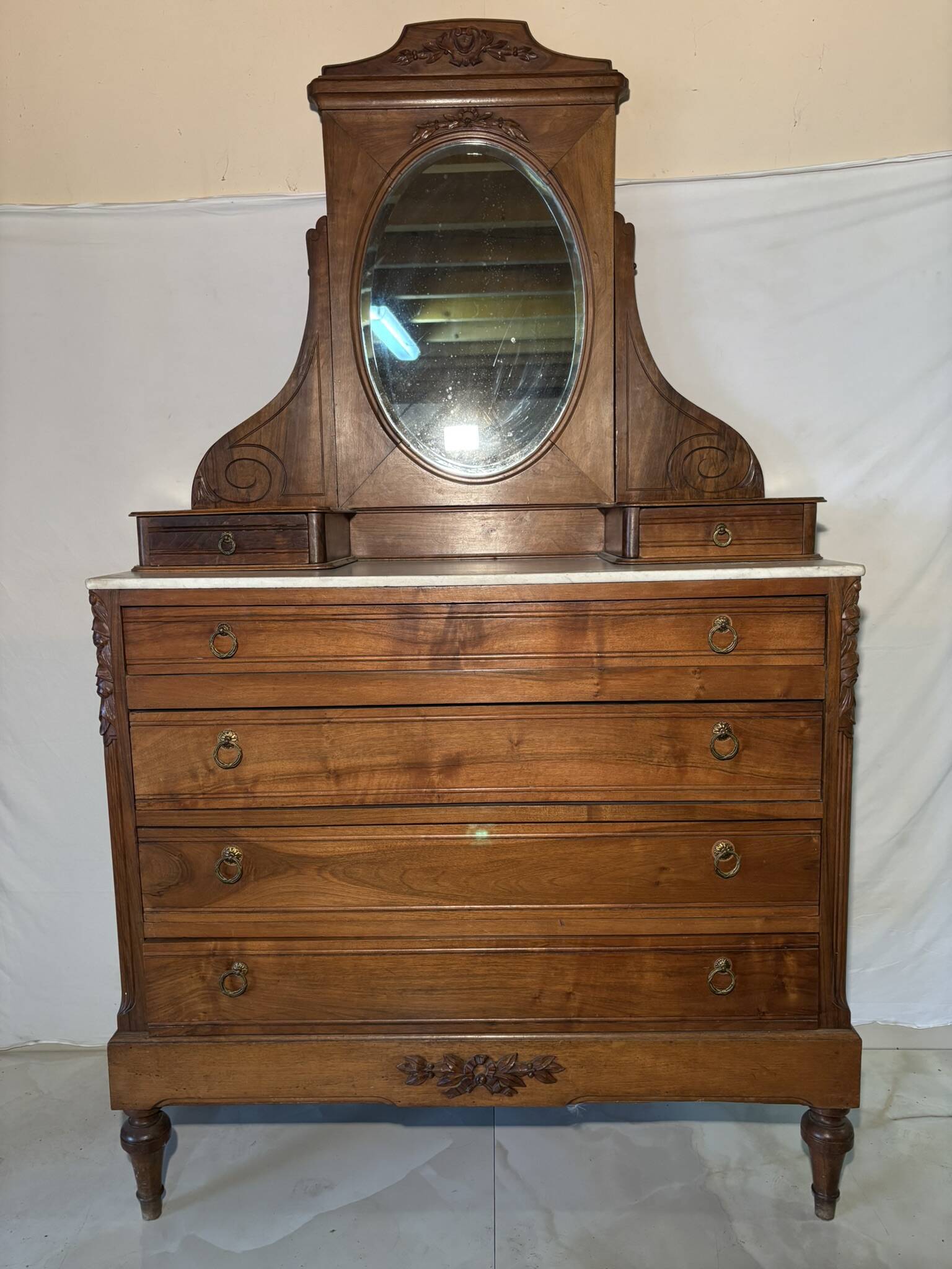 Antique carved wooden dressing table with marble and tilting oval mirror.
