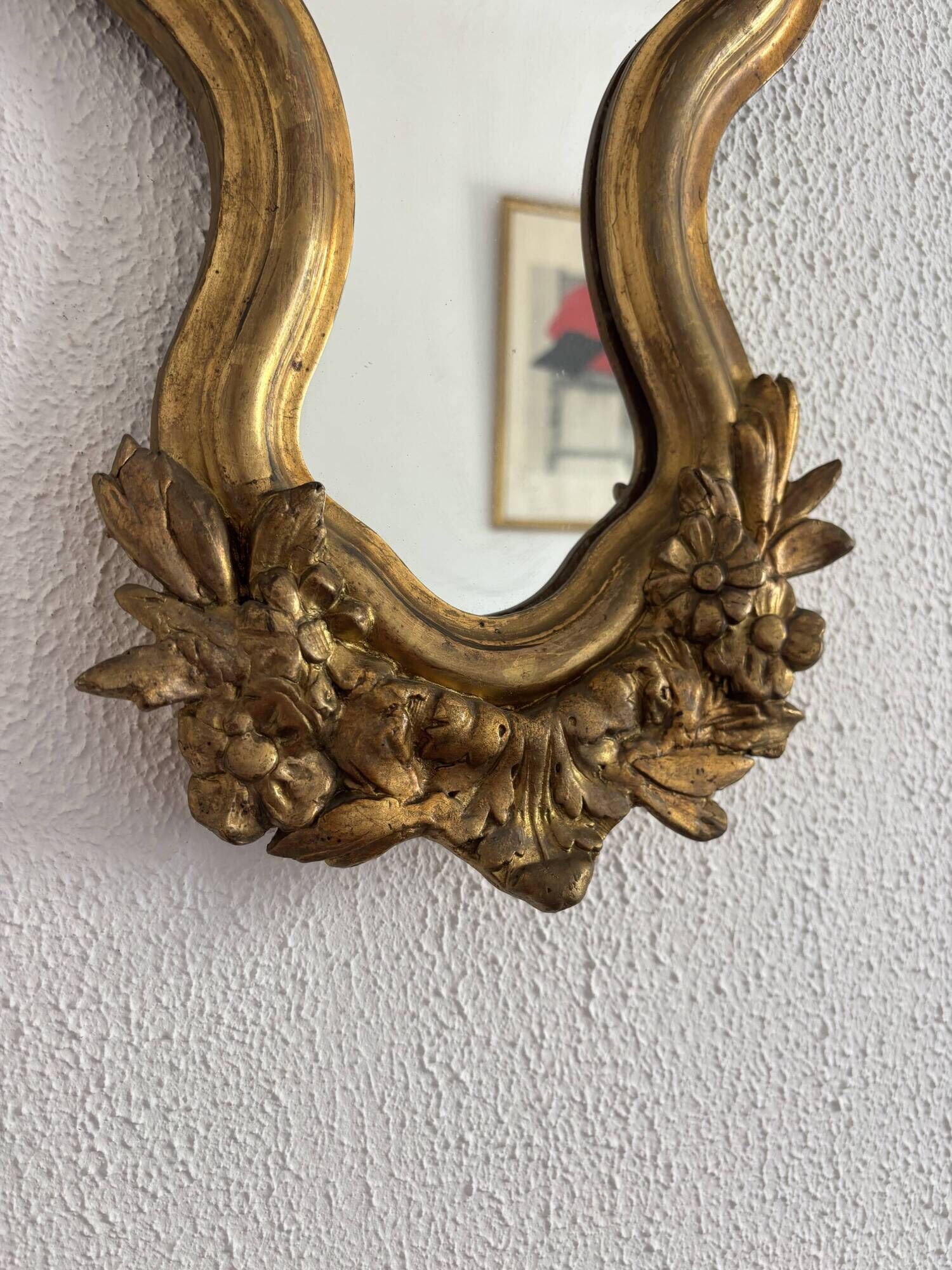 Antique rococo mirror with putti, gilded carved wood and stucco frame, 19th century.