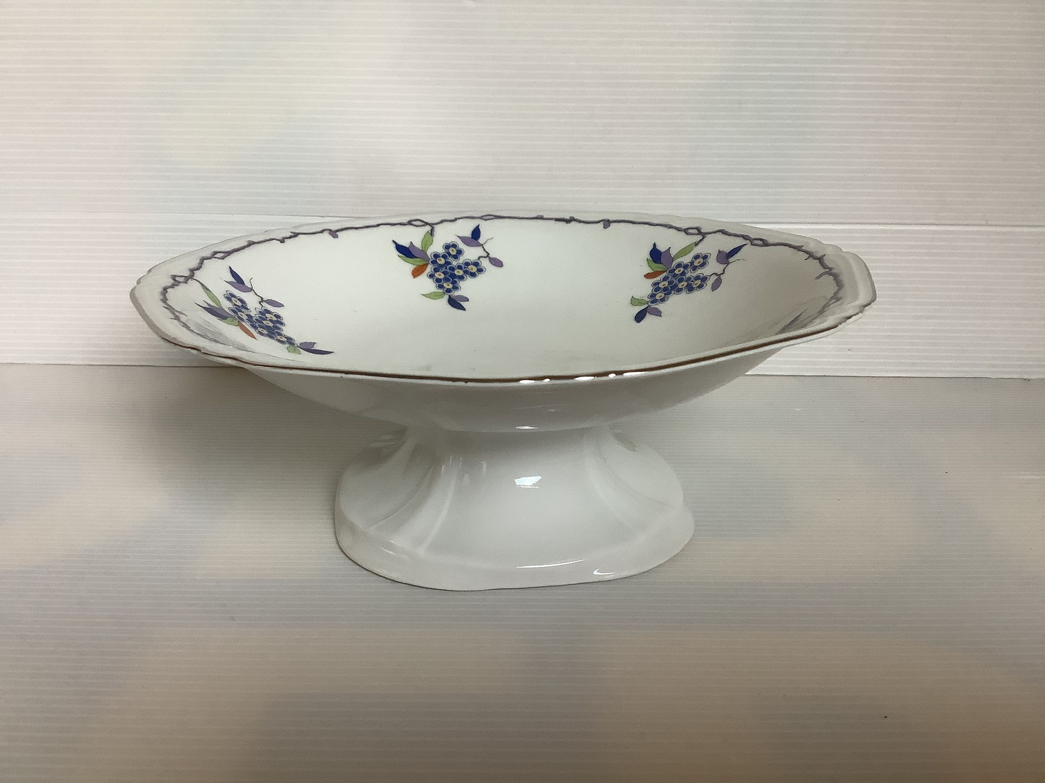 Old shower tray with silver trim and forget-me-not flowers.
