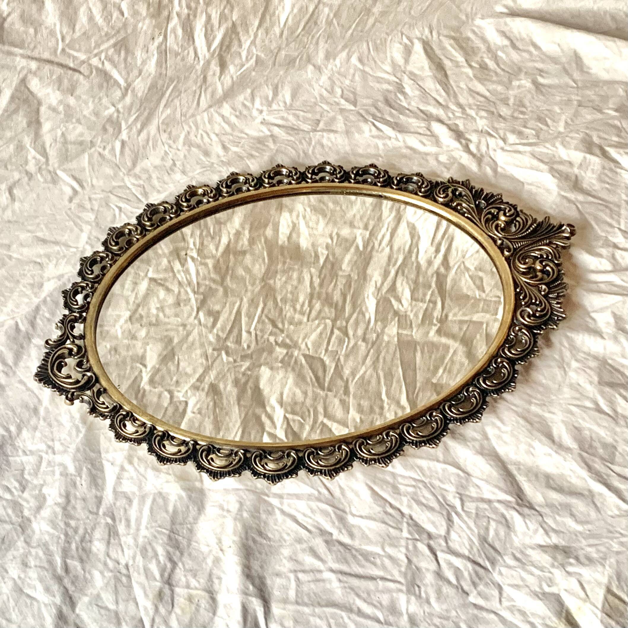 Old oval wall mirror in gilded brass