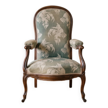 Antique Voltaire armchair in wood and green fabric with floral patterns.
