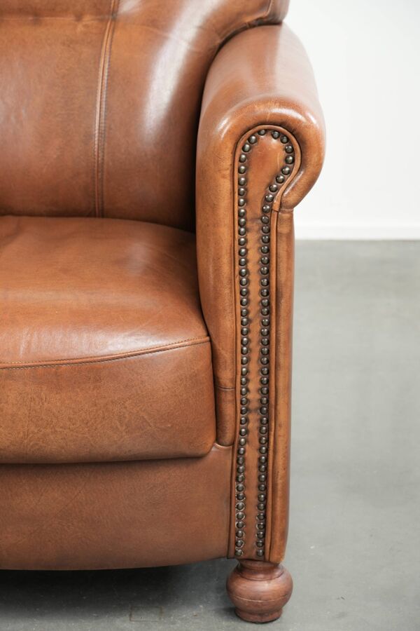 Fauteuil en cuir de peau de mouton avec finition décorative en clous raffinés.