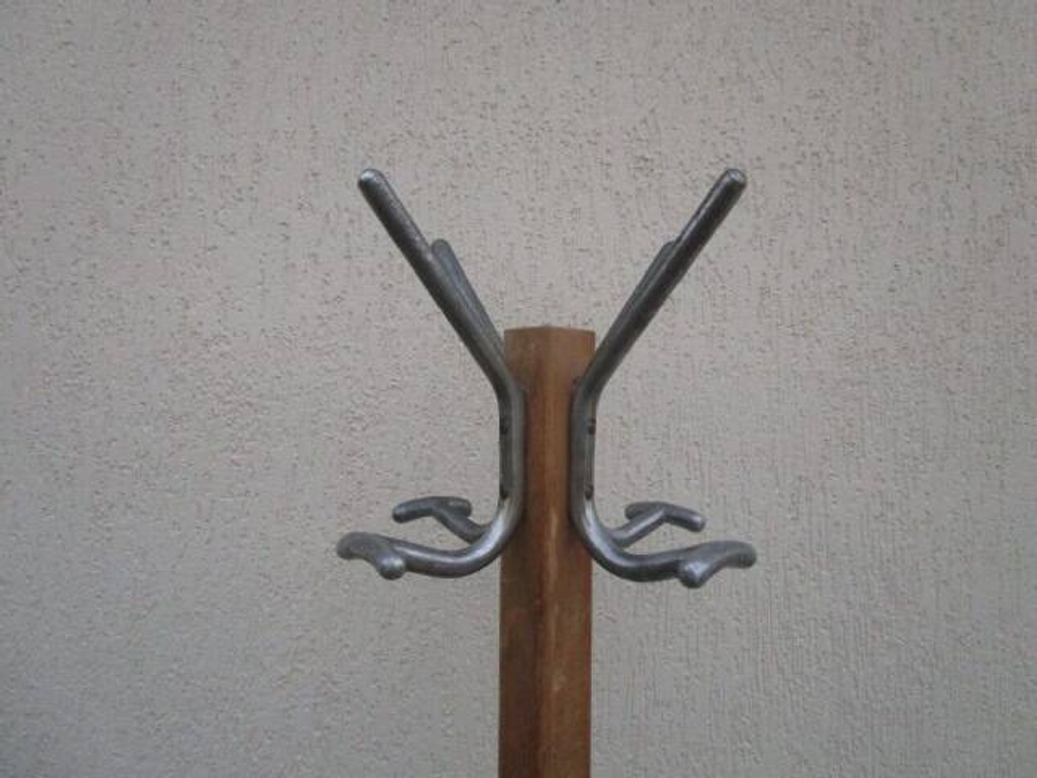 Antique light wood coat rack with splayed legs.