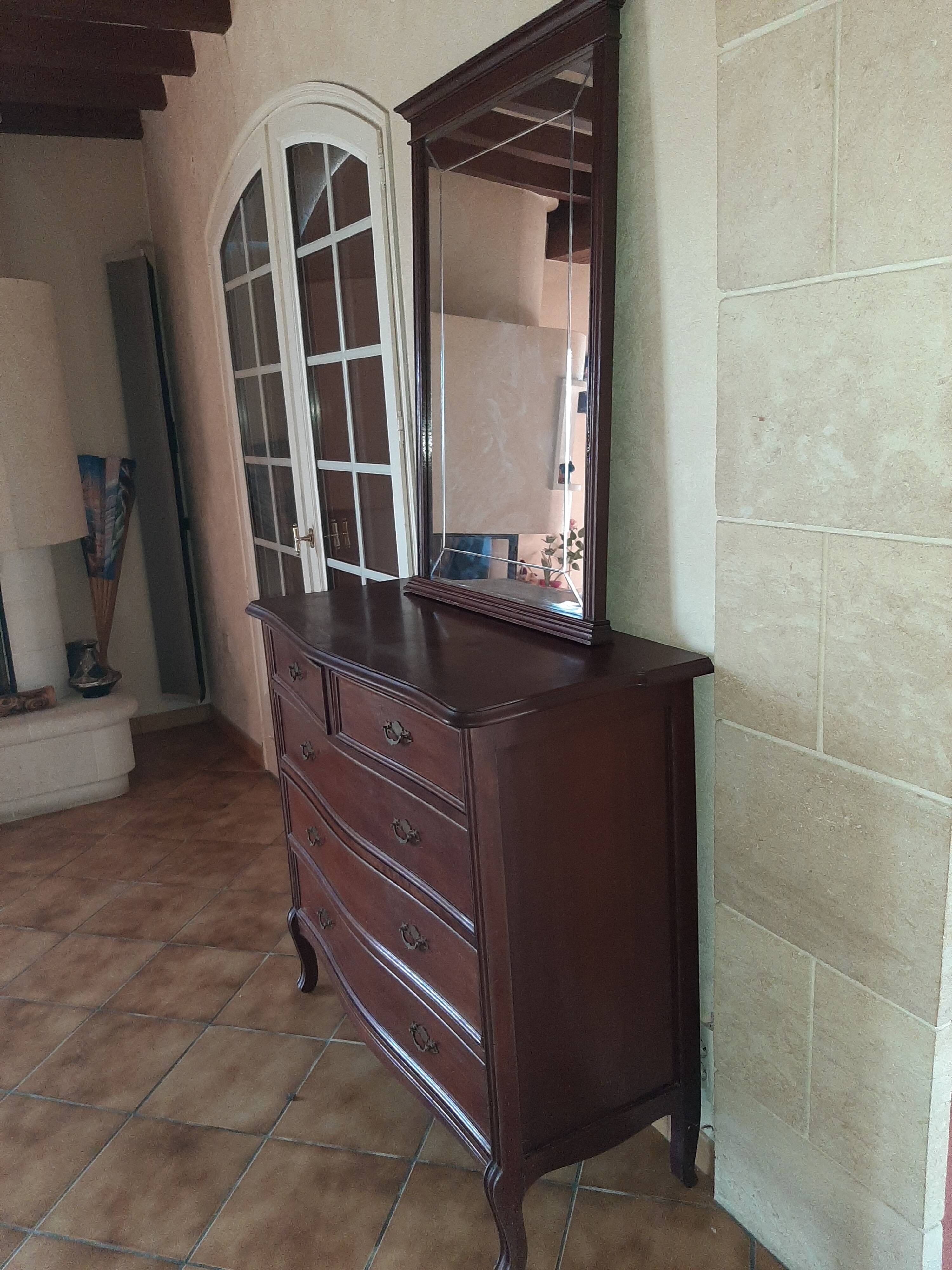 Style set: bevelled mirror and curved wooden chest of drawers.