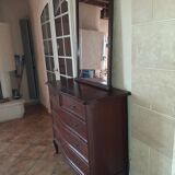 Style set: bevelled mirror and curved wooden chest of drawers.