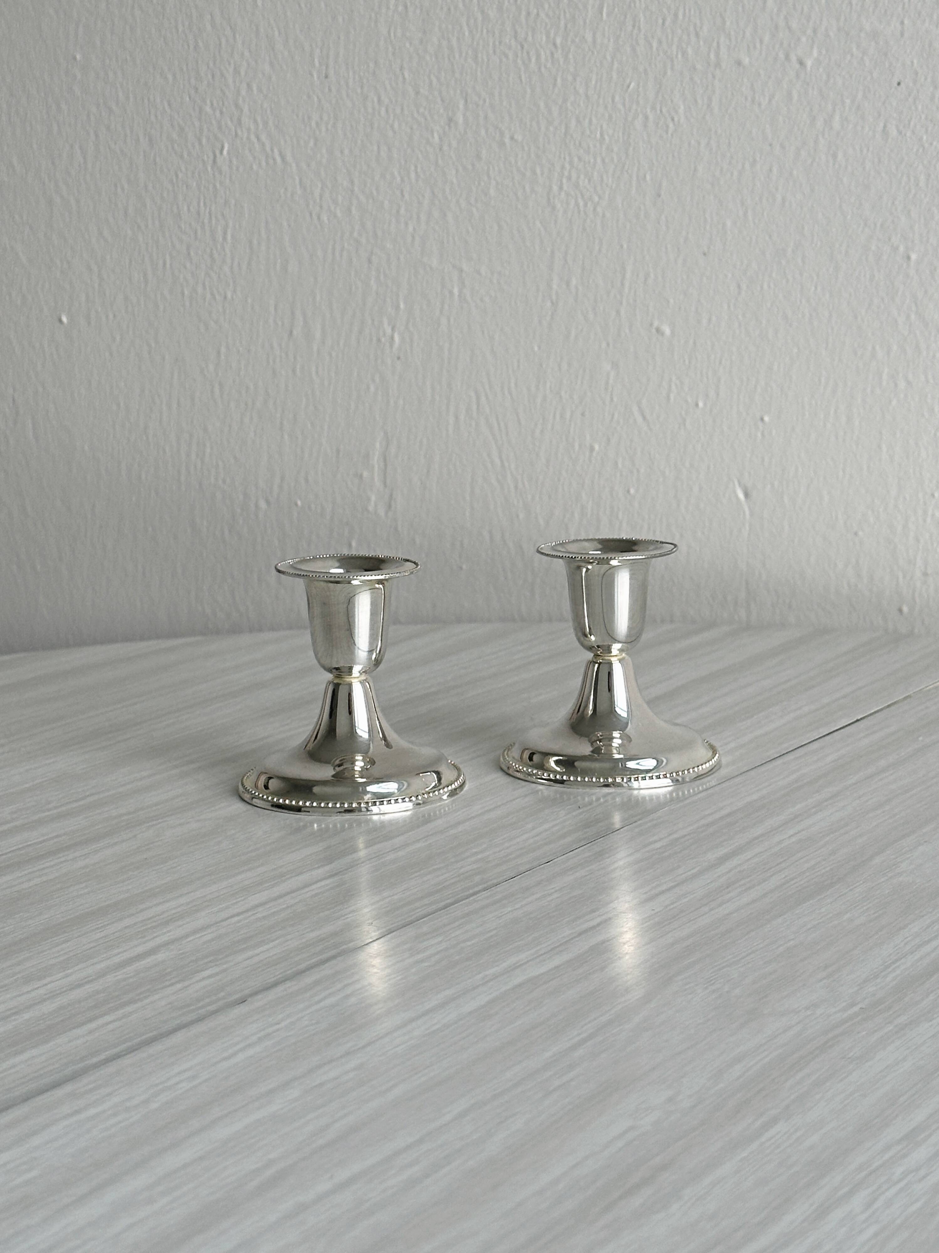 A pair of small silver-white metal candle holders.