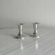 A pair of small silver-white metal candle holders.