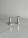 A pair of small silver-white metal candle holders.