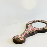 Vintage enameled metal hand mirror on wood