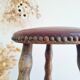 Antique tripod stool with turned wooden legs and leather seat.