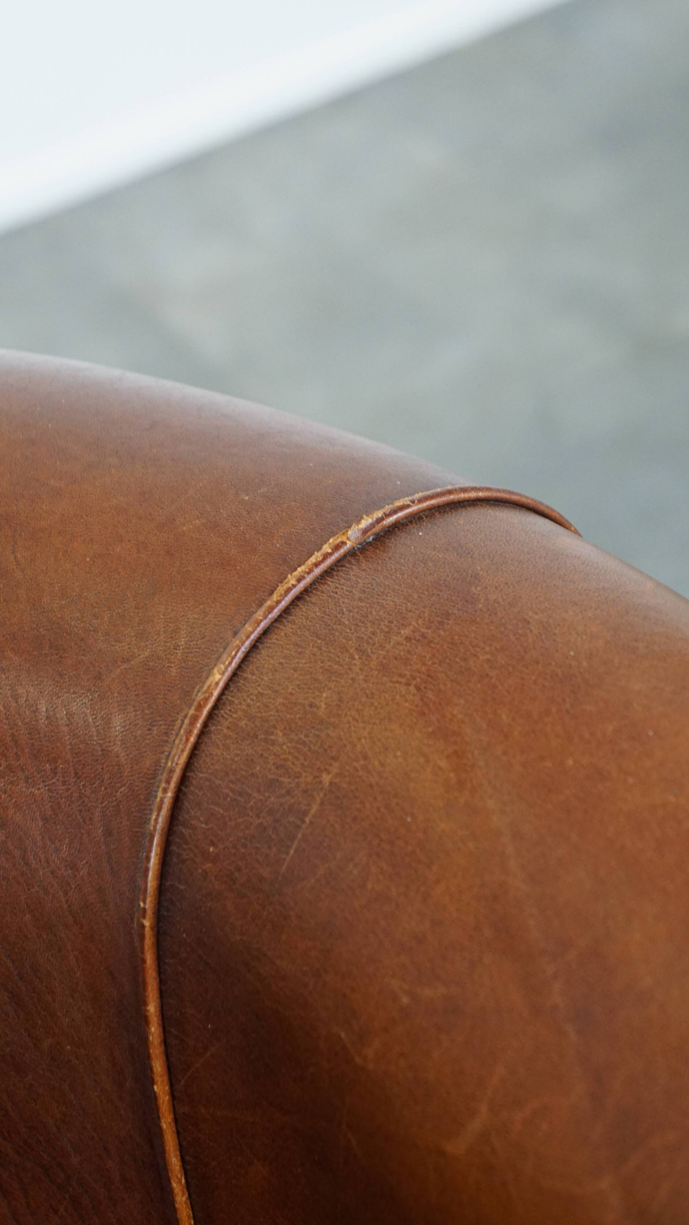 Sheep leather club chair in a cognac color and finished with piping