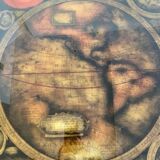 Table basse en bois exotique, garniture laiton et planisphère sous verre.