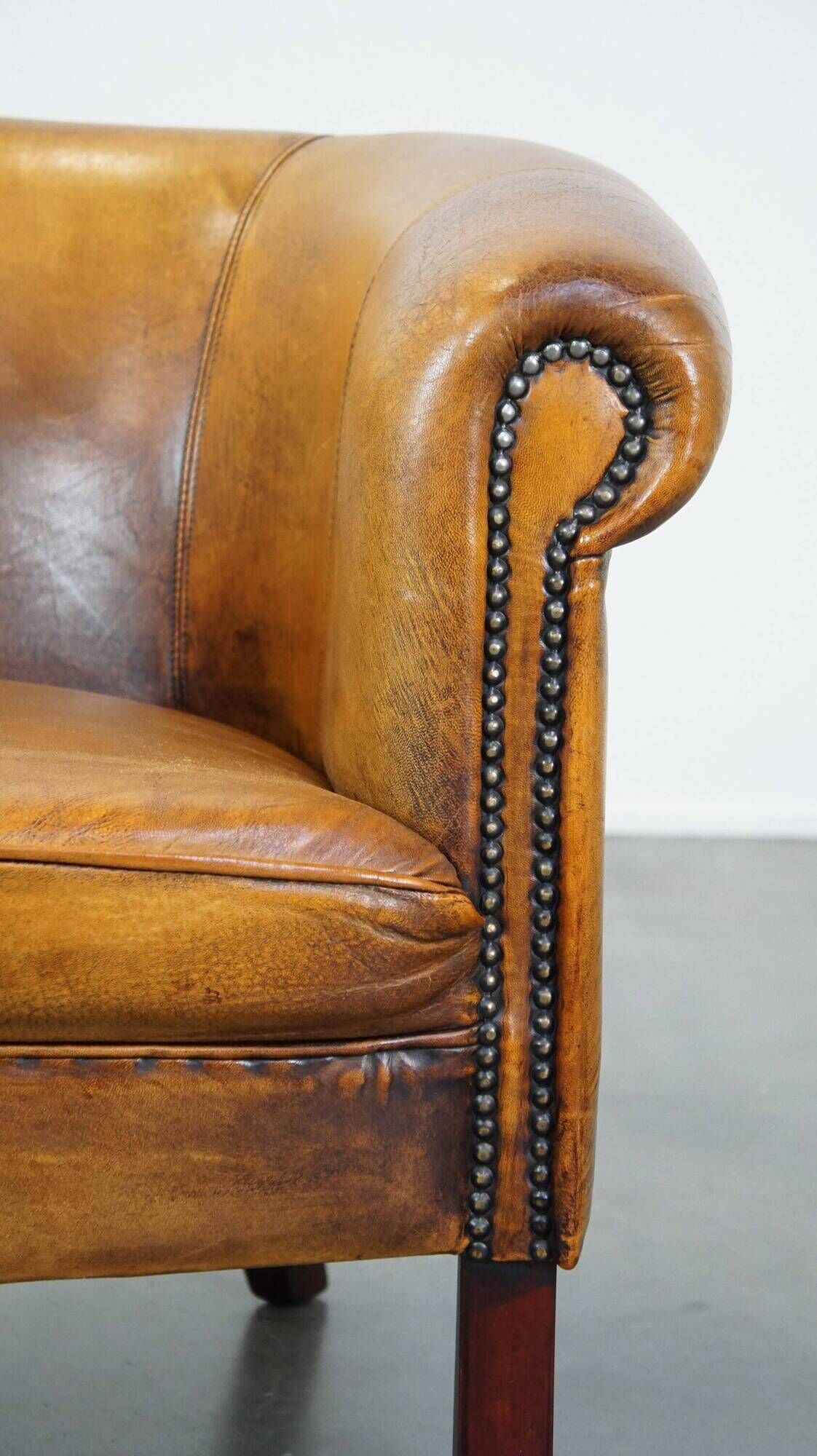 Fauteuil club en peau de mouton subtile avec finition cloutée décorative