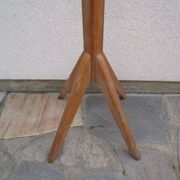 Antique light wood coat rack with splayed legs.