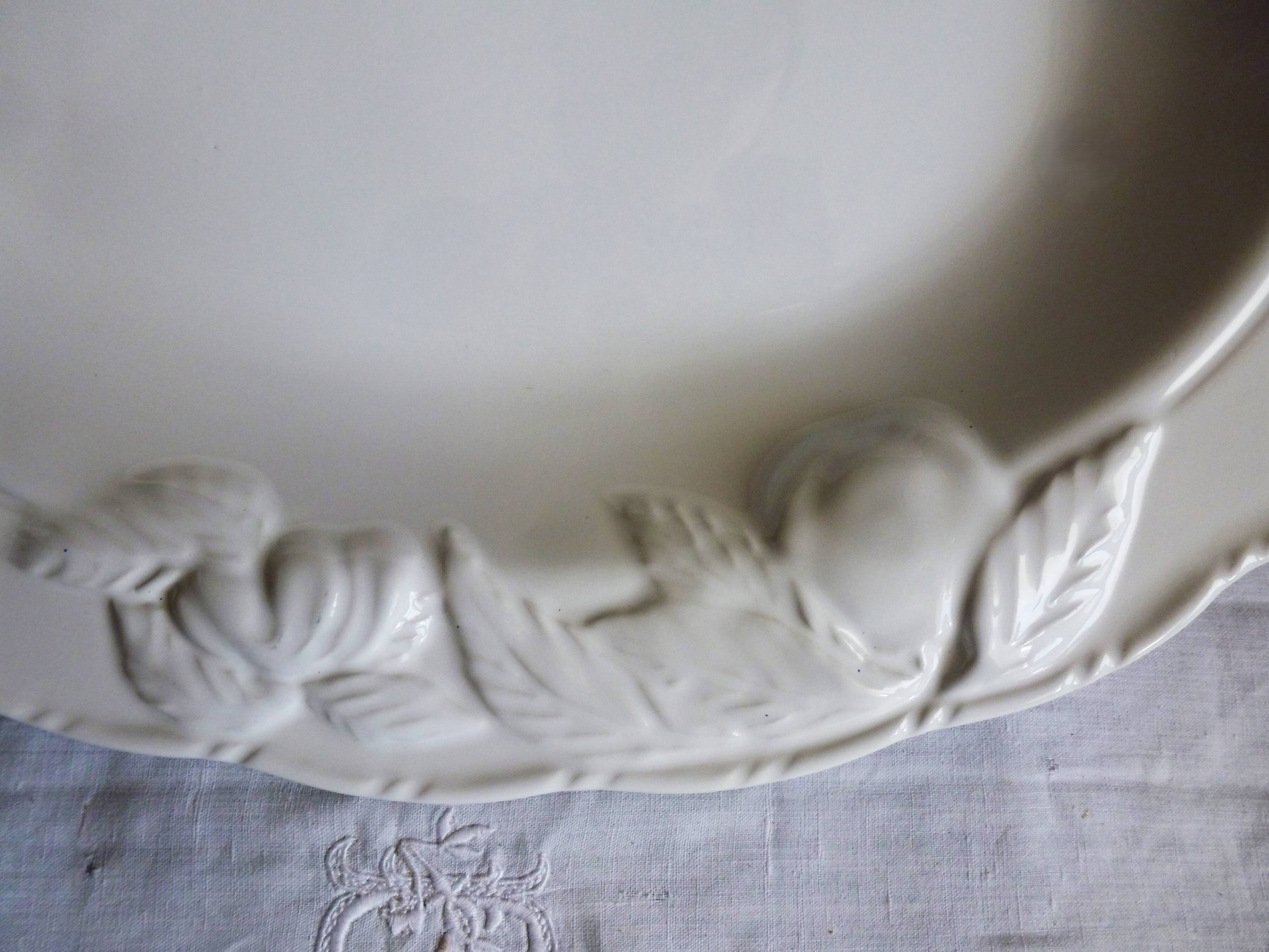 Oval white vegetable dish, an antique tableware piece in barbotine earthenware.
